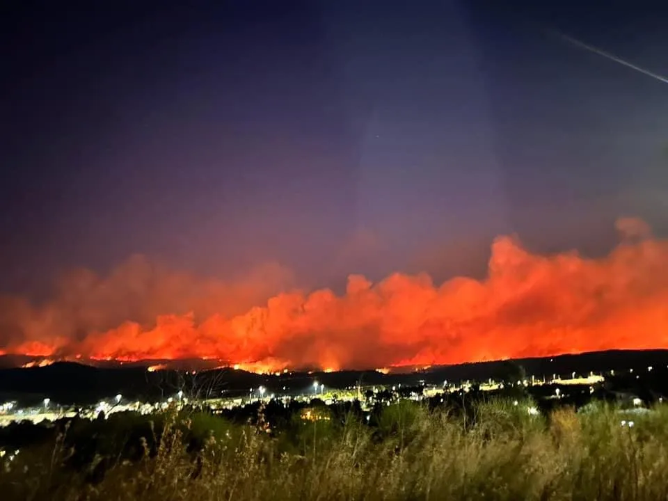 Brennende Wälder mit einem Dorf im Vordergrund.